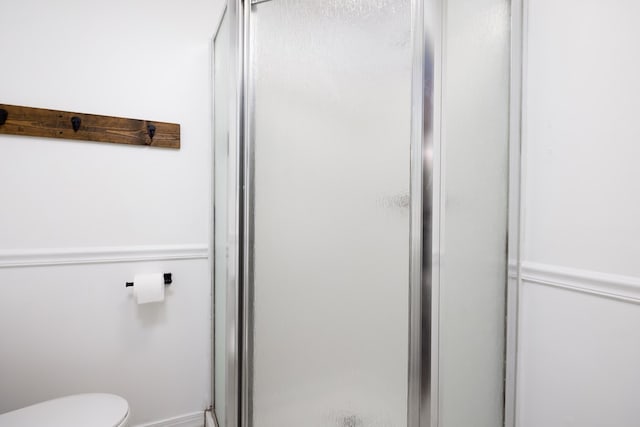 bathroom featuring toilet and a shower with door