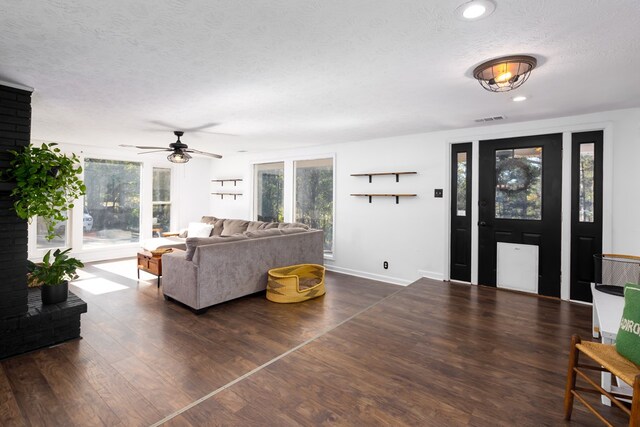 living room with a wealth of natural light, dark hardwood / wood-style flooring, ceiling fan, and a textured ceiling