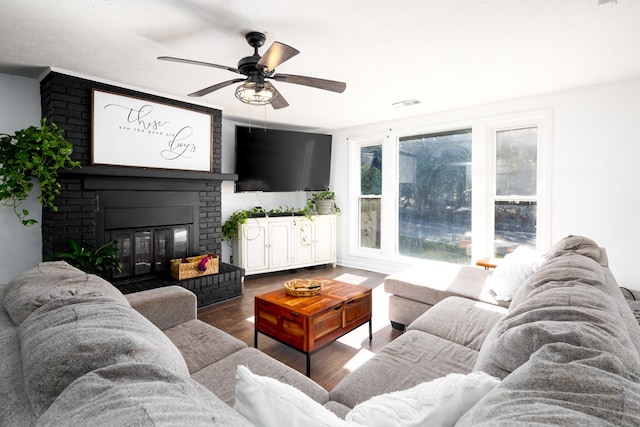 living room featuring ceiling fan, dark wood-type flooring, and a brick fireplace