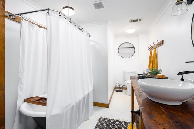 bathroom with tile patterned floors, crown molding, vanity, and toilet