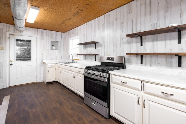 kitchen with white cabinets, sink, wooden walls, dark hardwood / wood-style floors, and stainless steel range with gas stovetop