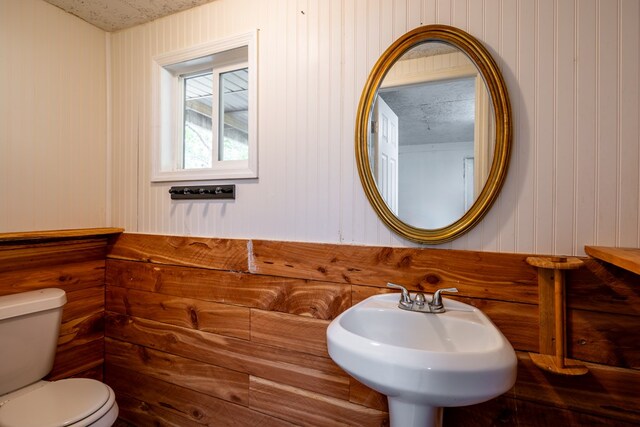 bathroom with wood walls, a textured ceiling, and toilet