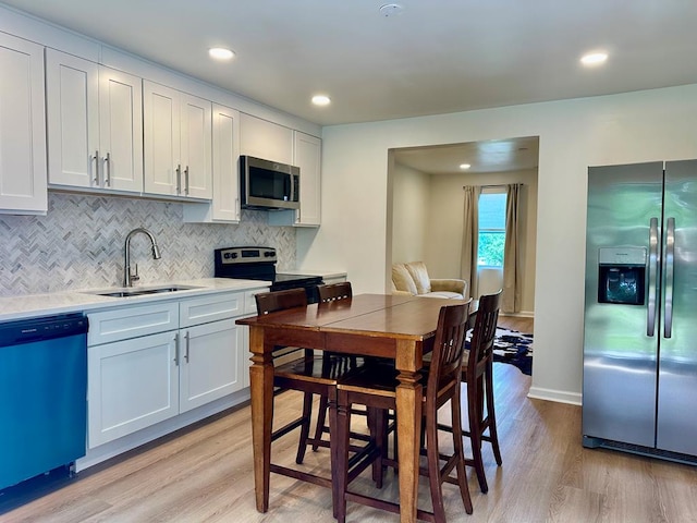 6231 Lynridge Ave, Columbus, GA 31909 - kitchen with stainless steel appliances, a sink, light wood-style flooring, tasteful backsplash, and light countertops