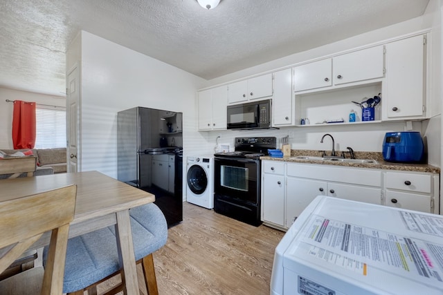 kitchen with sink, light hardwood / wood-style flooring, black appliances, white cabinets, and washer / clothes dryer