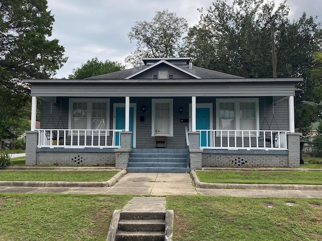 bungalow featuring covered porch and a front yard