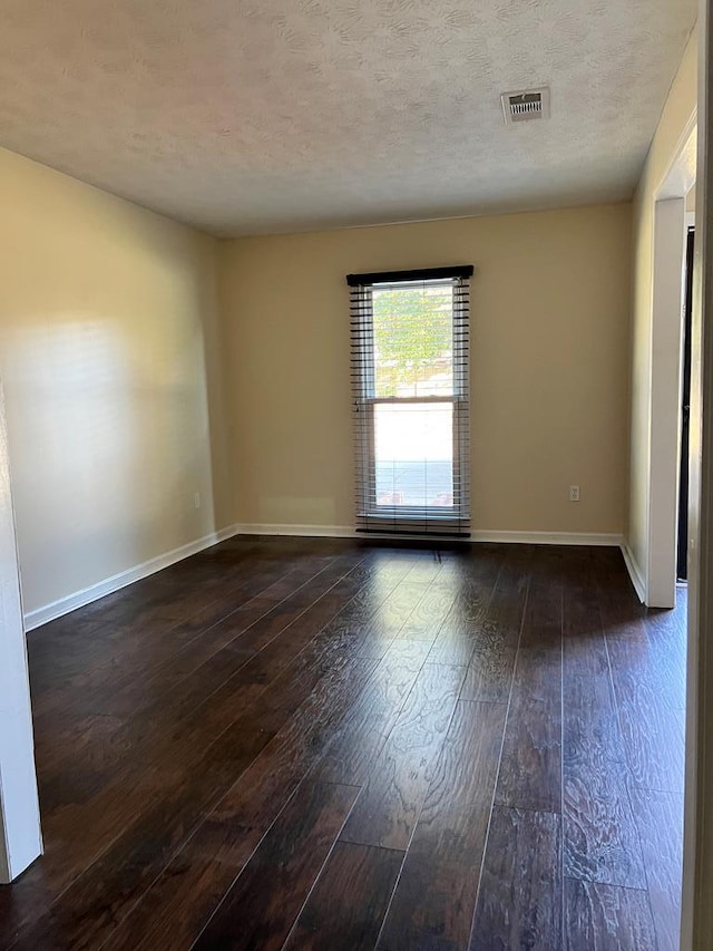 spare room with a textured ceiling and dark wood-type flooring