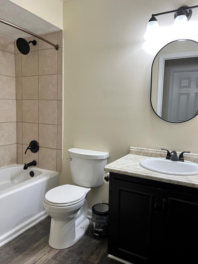 full bathroom with toilet, vanity, wood-type flooring, and tiled shower / bath