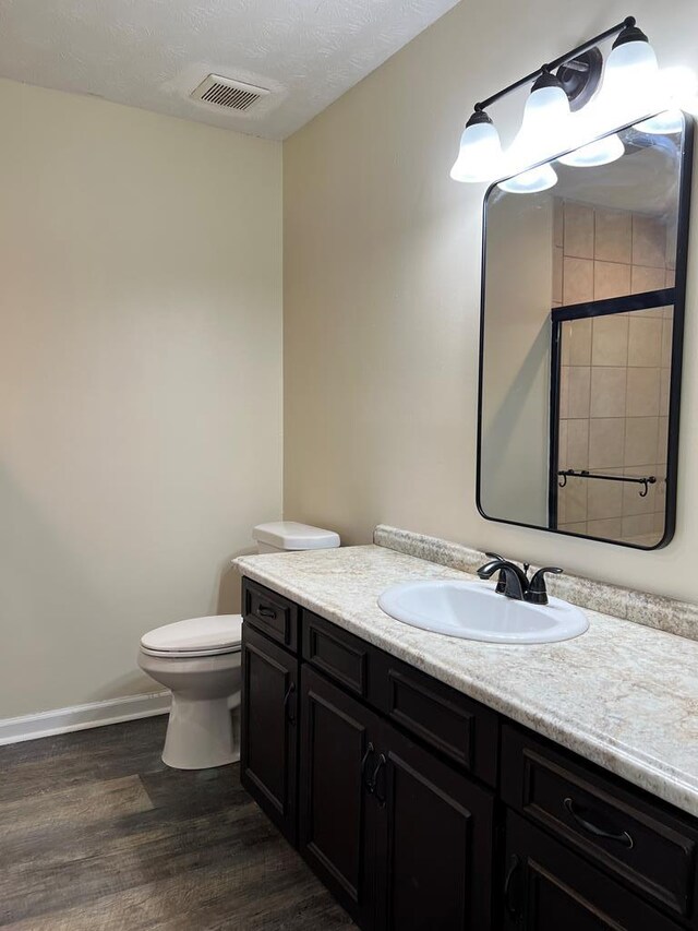 bathroom with hardwood / wood-style floors, vanity, a textured ceiling, and toilet