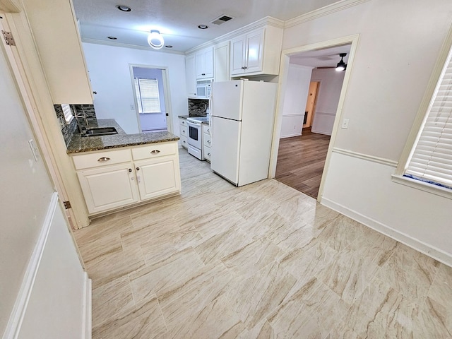 kitchen with backsplash, white appliances, crown molding, dark stone countertops, and white cabinetry