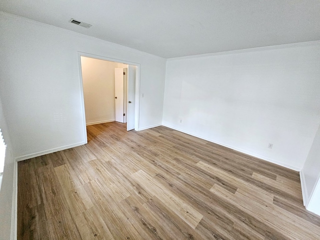 empty room with light hardwood / wood-style floors and ornamental molding