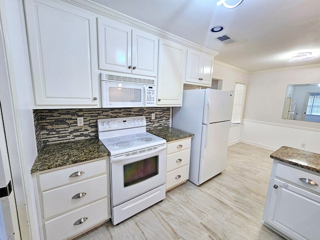 kitchen with white cabinetry, backsplash, crown molding, dark stone counters, and white appliances