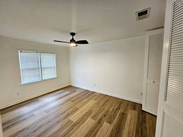 unfurnished bedroom featuring hardwood / wood-style floors, a closet, ceiling fan, and ornamental molding