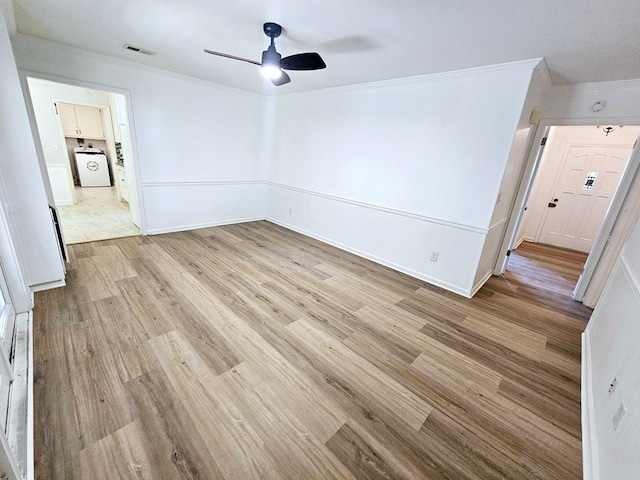 spare room featuring washer / clothes dryer, light hardwood / wood-style flooring, ceiling fan, and crown molding