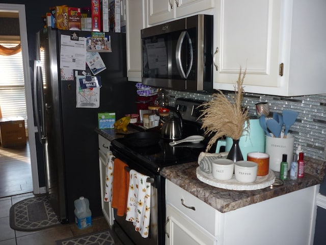 kitchen with dark countertops, stainless steel microwave, electric range, white cabinetry, and tile patterned floors