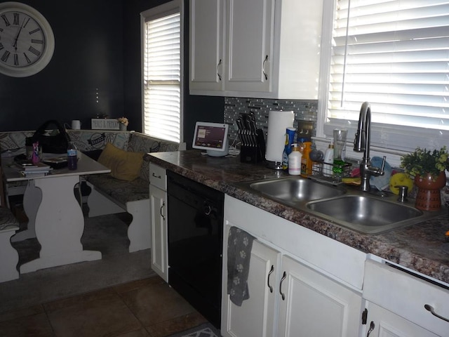 kitchen featuring a sink, white cabinetry, black dishwasher, a wealth of natural light, and dark countertops