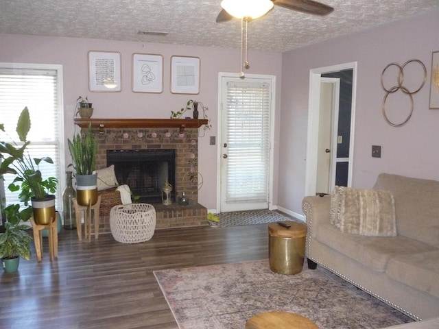 living area with dark wood-style floors, a fireplace, a textured ceiling, and baseboards