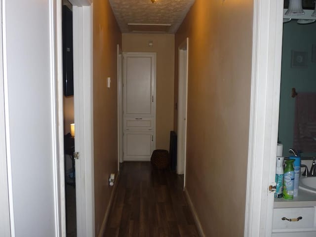 hallway with attic access, baseboards, and dark wood-style floors