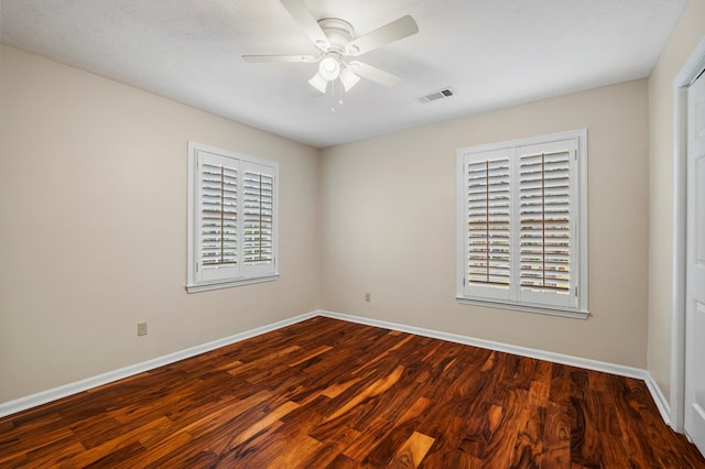 spare room featuring a ceiling fan, wood finished floors, visible vents, and baseboards