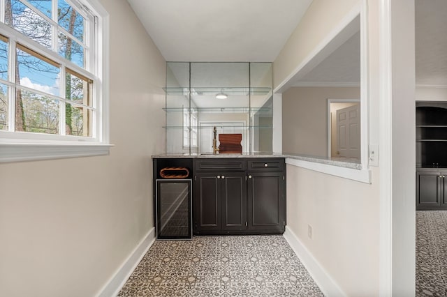 bar with ornamental molding, a sink, wine cooler, indoor wet bar, and baseboards