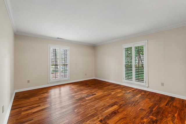 empty room with crown molding, wood finished floors, visible vents, and baseboards