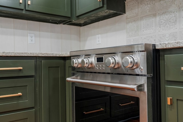 details featuring green cabinetry, light stone counters, and stainless steel stove