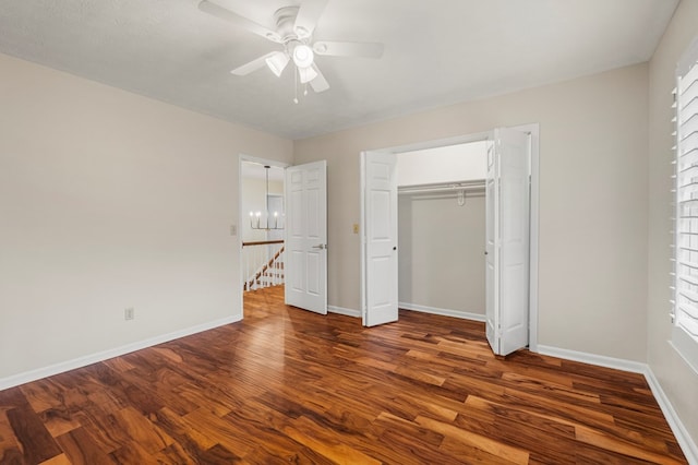 unfurnished bedroom with ceiling fan with notable chandelier, wood finished floors, baseboards, and a closet