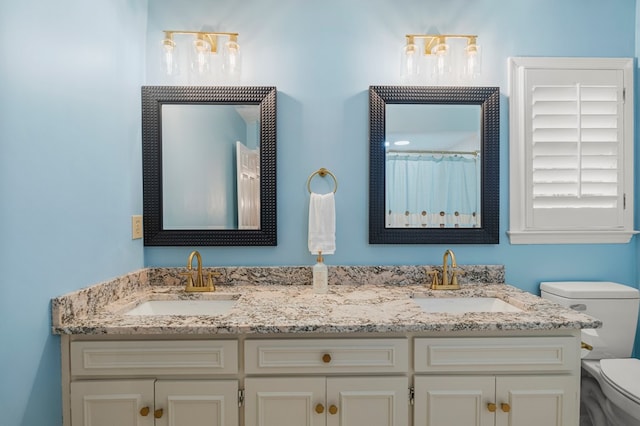 bathroom with a sink, toilet, and double vanity