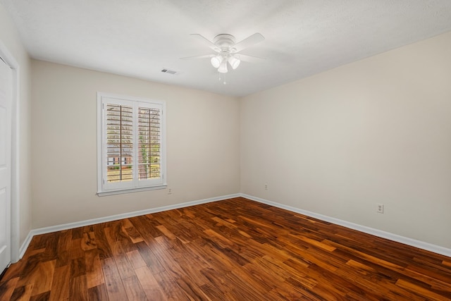 empty room featuring visible vents, a ceiling fan, baseboards, and wood finished floors