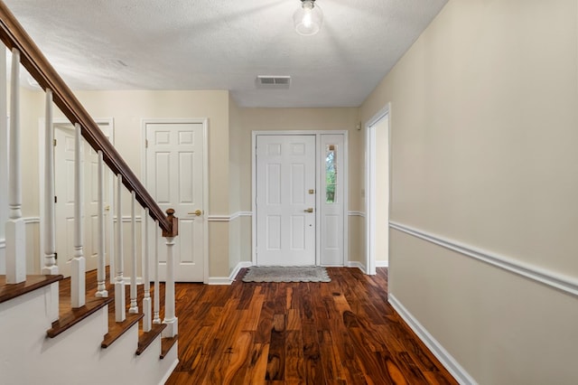 entryway with dark wood finished floors, stairs, baseboards, and a textured ceiling