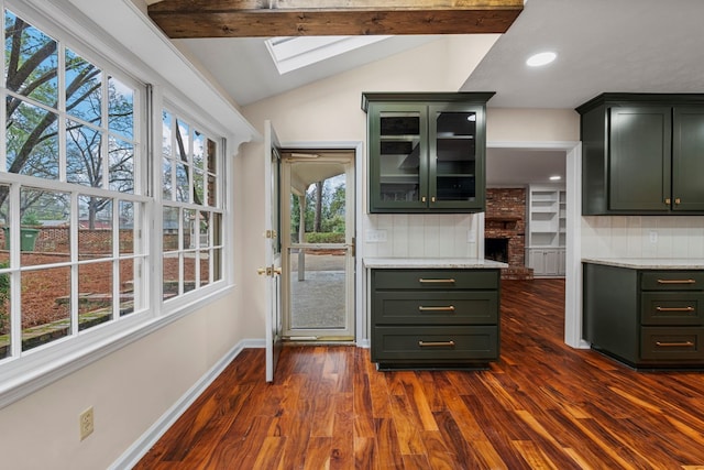 kitchen with baseboards, dark wood finished floors, glass insert cabinets, green cabinets, and lofted ceiling with skylight