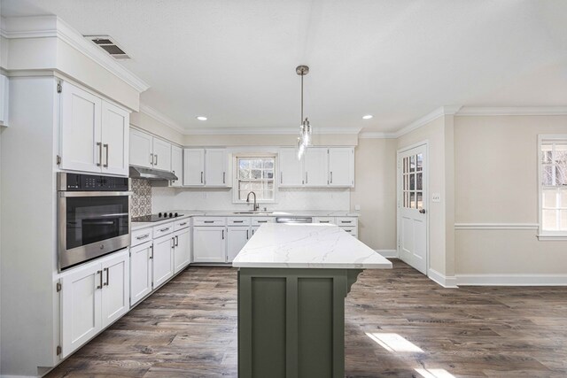 kitchen featuring stainless steel appliances, light stone counters, white cabinets, a kitchen island, and decorative light fixtures