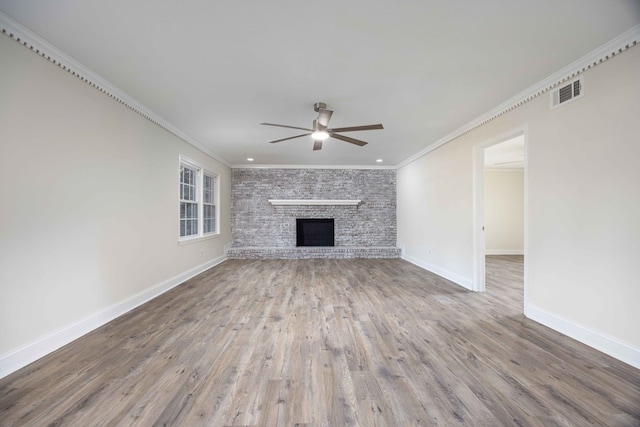 unfurnished living room with a fireplace, wood-type flooring, ornamental molding, and ceiling fan