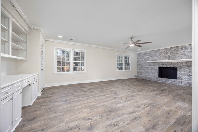 unfurnished living room with crown molding, a fireplace, ceiling fan, and light hardwood / wood-style flooring