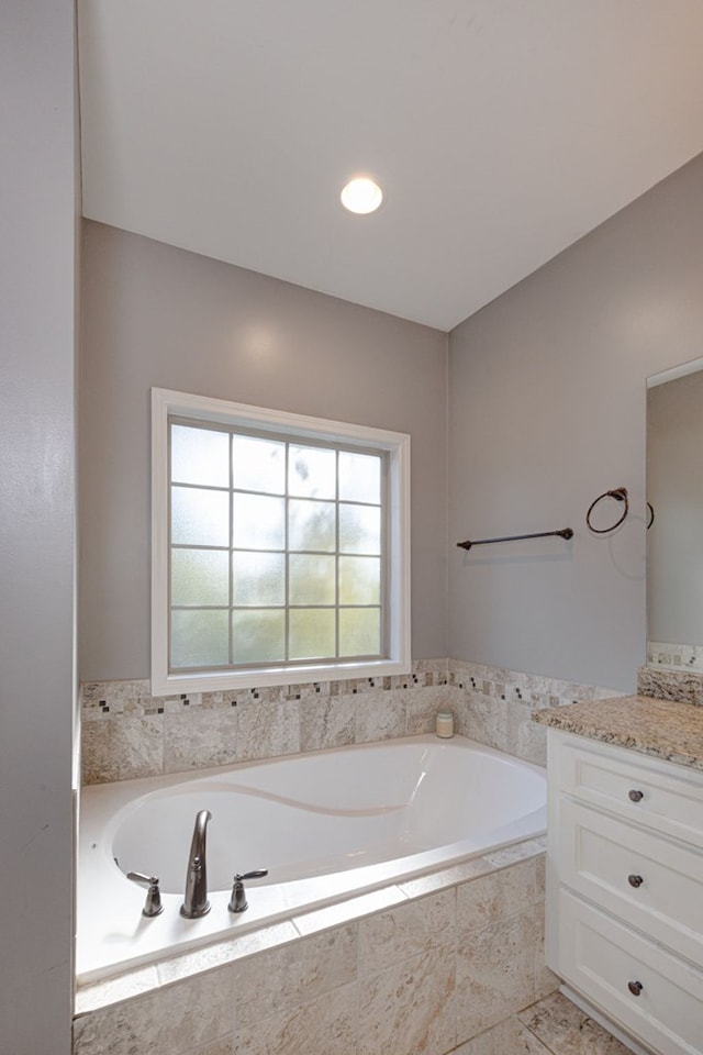 bathroom featuring vanity and tiled bath