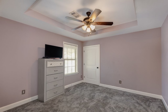 unfurnished bedroom with ceiling fan, carpet flooring, and a tray ceiling