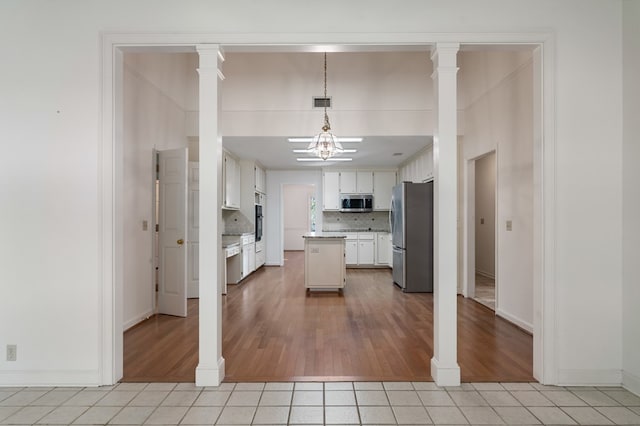 kitchen featuring white cabinetry, hanging light fixtures, stainless steel appliances, and light wood-type flooring