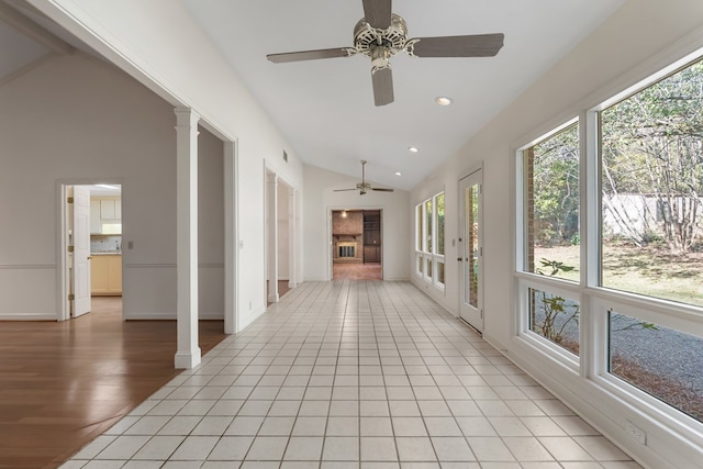 unfurnished sunroom featuring ornate columns, ceiling fan, french doors, and lofted ceiling