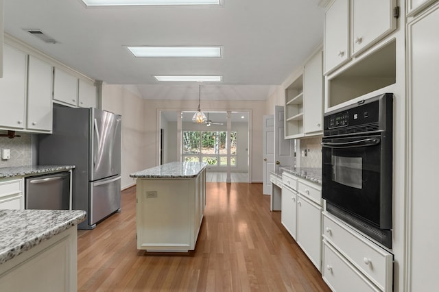 kitchen featuring pendant lighting, backsplash, light stone countertops, light wood-type flooring, and stainless steel appliances