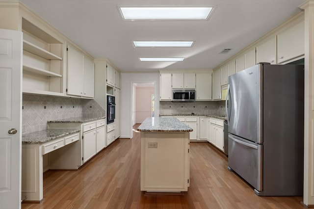 kitchen featuring black appliances, a center island, light hardwood / wood-style floors, and tasteful backsplash