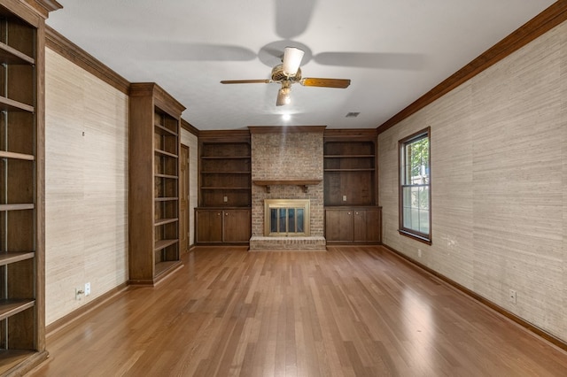 unfurnished living room with ceiling fan, ornamental molding, a fireplace, and light hardwood / wood-style flooring