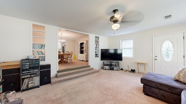 living area featuring visible vents, a textured ceiling, carpet, and ceiling fan with notable chandelier
