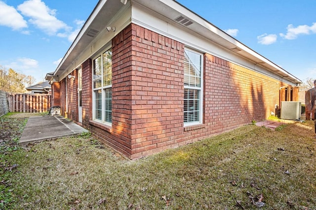 view of home's exterior with a patio, central AC, brick siding, fence, and a lawn