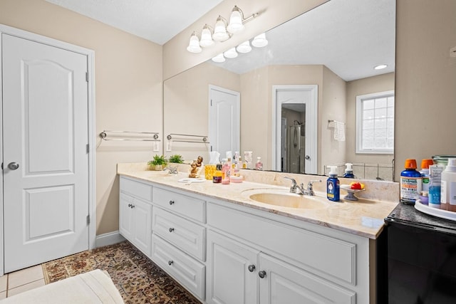 bathroom with double vanity, baseboards, a sink, and tile patterned floors