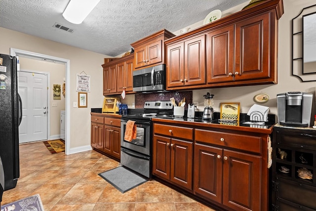 kitchen with baseboards, visible vents, dark countertops, stainless steel appliances, and a textured ceiling