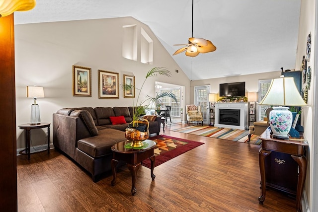 living room featuring baseboards, ceiling fan, wood finished floors, a fireplace, and high vaulted ceiling