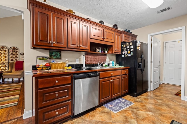 kitchen featuring visible vents, dishwasher, black fridge, a textured ceiling, and a sink