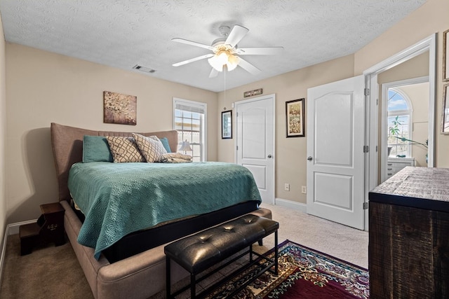 bedroom with a textured ceiling, multiple windows, visible vents, and carpet flooring