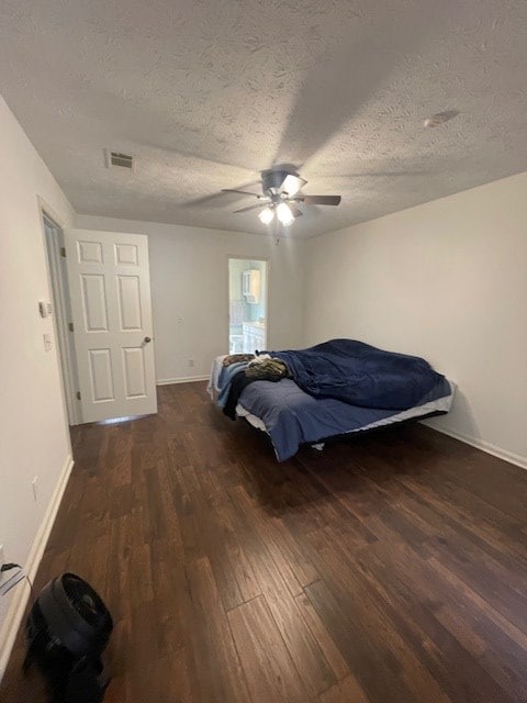 bedroom with a textured ceiling, wood finished floors, visible vents, and baseboards