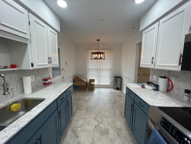 kitchen featuring stainless steel electric range, a sink, decorative backsplash, white cabinetry, and blue cabinets