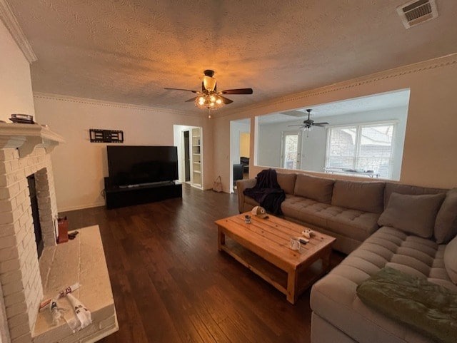 living area featuring visible vents, dark wood-type flooring, a fireplace, and crown molding